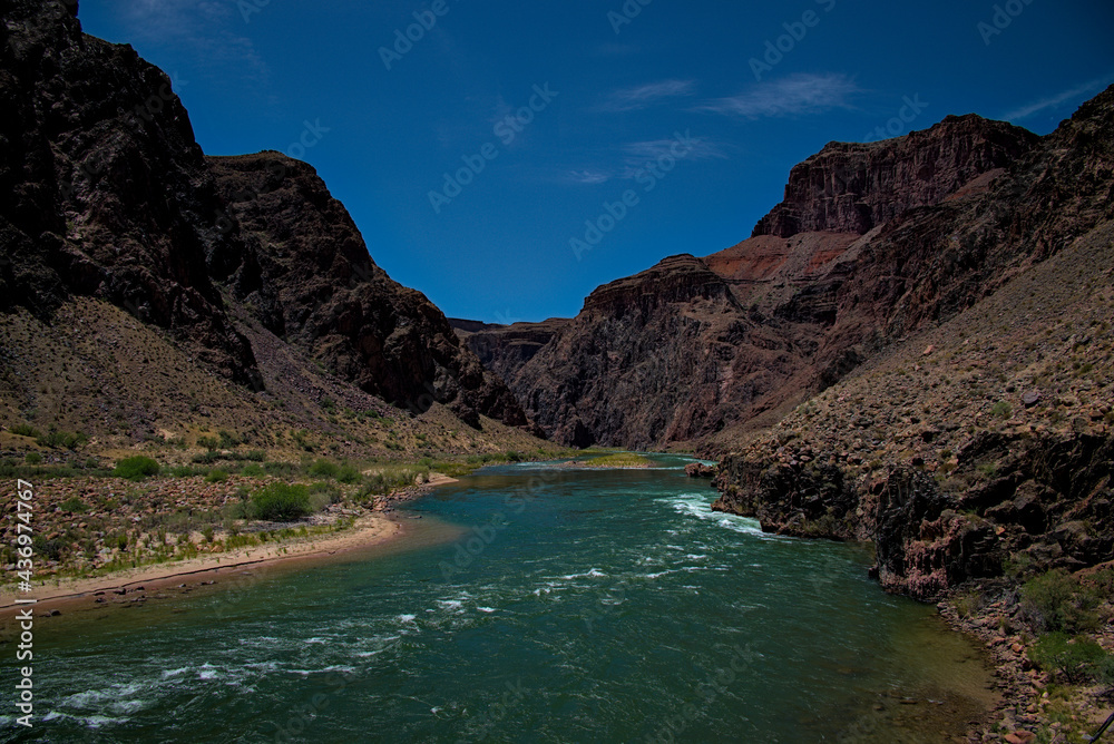 Grand canyon valley colorado river rushing under silver bridge on bright angel trail providing water to the southwestern united states of america.