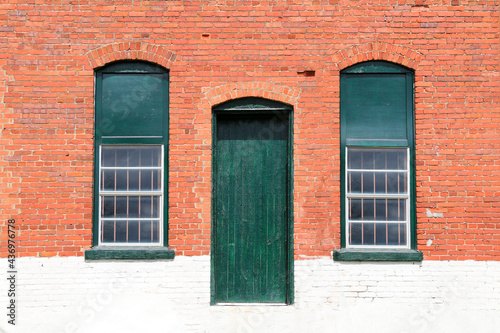 old town village red brick and white painted abandoned factory warehouse store door and windows trimmed in green