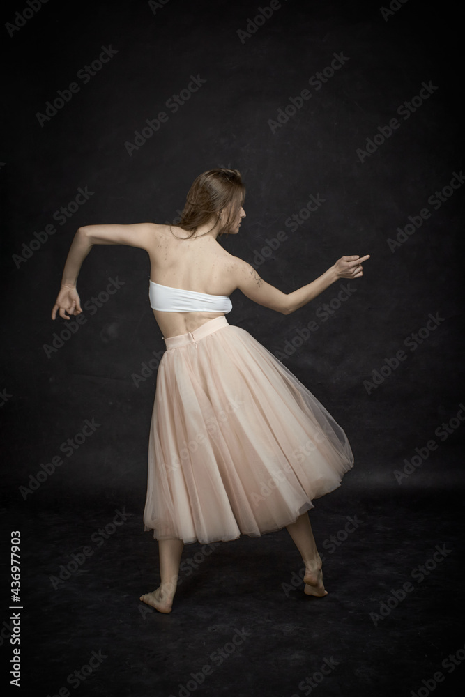Fototapeta premium Young girl in white top and peach skirt dancing