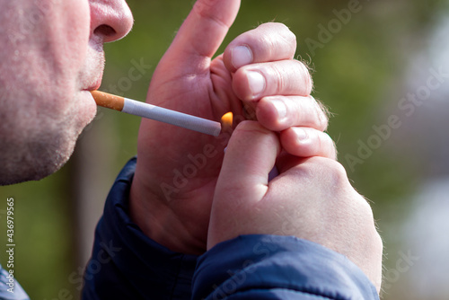 Cropped close up man light a cigarette outdoors