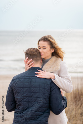 young beautiful stylish couple in spring on the beach. Hug each other and enjoy a warm spring evening.Close up.