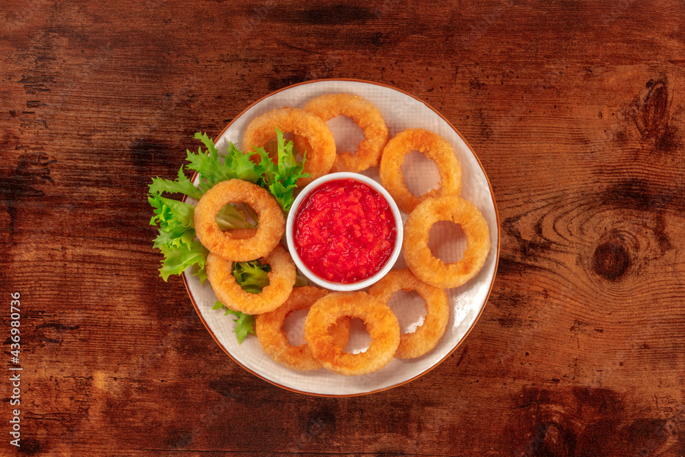 Squid rings. Deep fried calamari rings with lettuce and ketchup, shot from the top on a dark rustic wooden background Squid rings. Deep fried calamari rings with lettuce and ketchup, shot from the top on a dark rustic wooden background