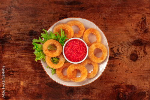 Squid rings. Deep fried calamari rings with lettuce and ketchup, shot from the top on a dark rustic wooden background