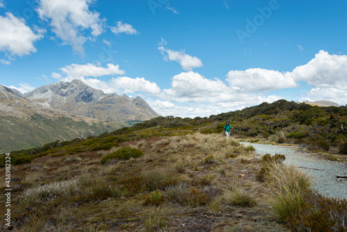 A man hiking on the Key Summit under blue sky with long white clouds  Routeburn Track  South Island