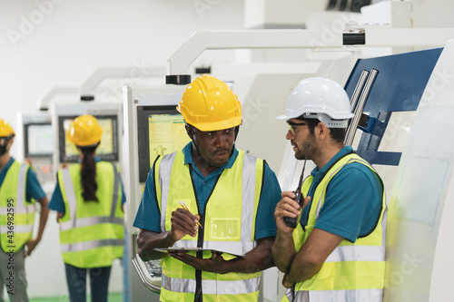 Caucasian and African worker discuss together in factory production line machine. Concept of multi ethnic group of people and diversity with copy space.