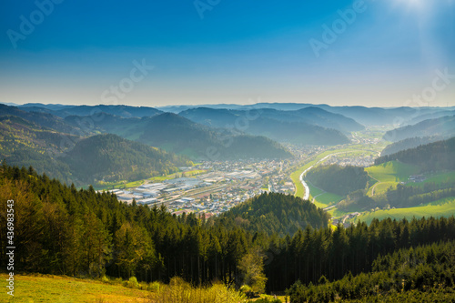 Germany, Aerial drone view above endless valley surrounded by green tree covered mountains and houses of city hausach im kinzigtal