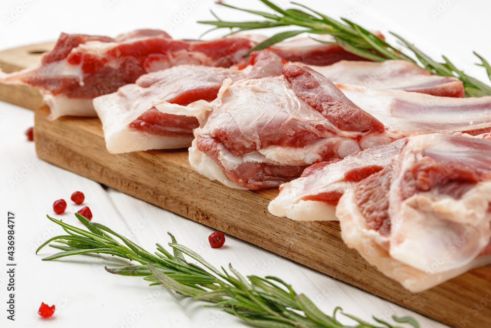 Raw meat ribs on wooden board on white background