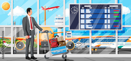 Man And Hand Truck Full Of Bags In Terminal Interior. Arrival Departure Board. Airport Luggage Trolley. Hand Cart. Handcart For Baggage Or Luggage. Transportation Equipment. Flat Vector Illustration