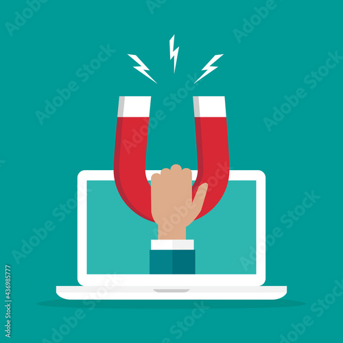 Hand with red horseshoe magnet on laptop screen. Online business.