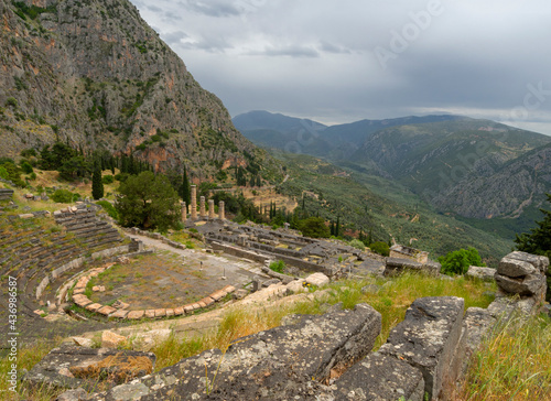 Panoramic view on ancient theater and temple of Apollo with columns in Delphi against the background of mountains and the sky with clouds in Greece photo