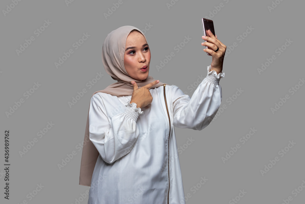 Woman in hijab takes a selfie using a smart phone Woman in hijab takes a selfie using a smart phone
