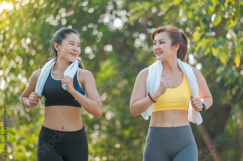 Two Asian women jogging and exercising in the park.