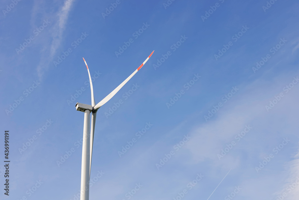 Windmill for electric power production against the blue sky.