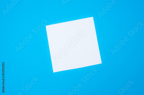 Blank white To Do List Sticker. Close up of reminder note paper on the blue background. Copy space. Minimalism, original and creative photo.