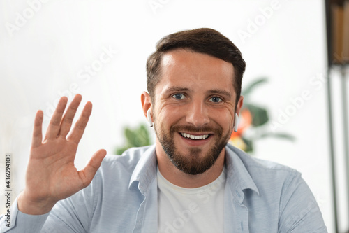 Head shot portrait millennial guy makes video call looks at camera and smiling, Young happy man shows gesture of greeting employee at online meeting, hiring by video conference, online education