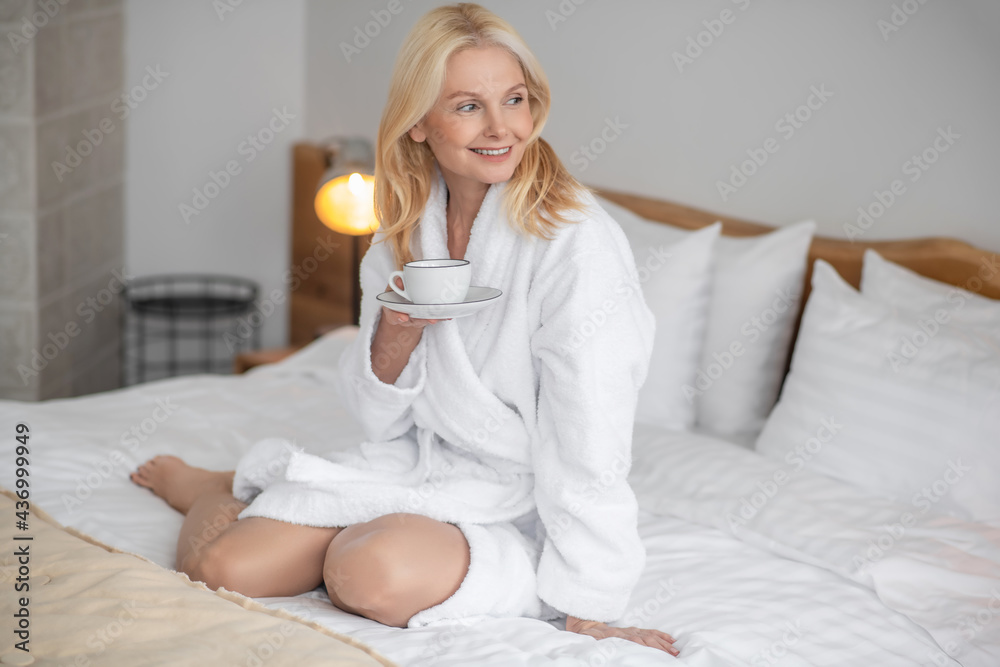 Pretty blonde woman having her morning tea in the bedroom Pretty blonde woman having her morning tea in the bedroom
