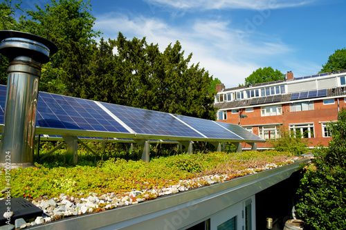 Solar panels on a green roof with flowering sedum plants. Sedum rooftop garden with photovoltaic cells for sustainable energy.