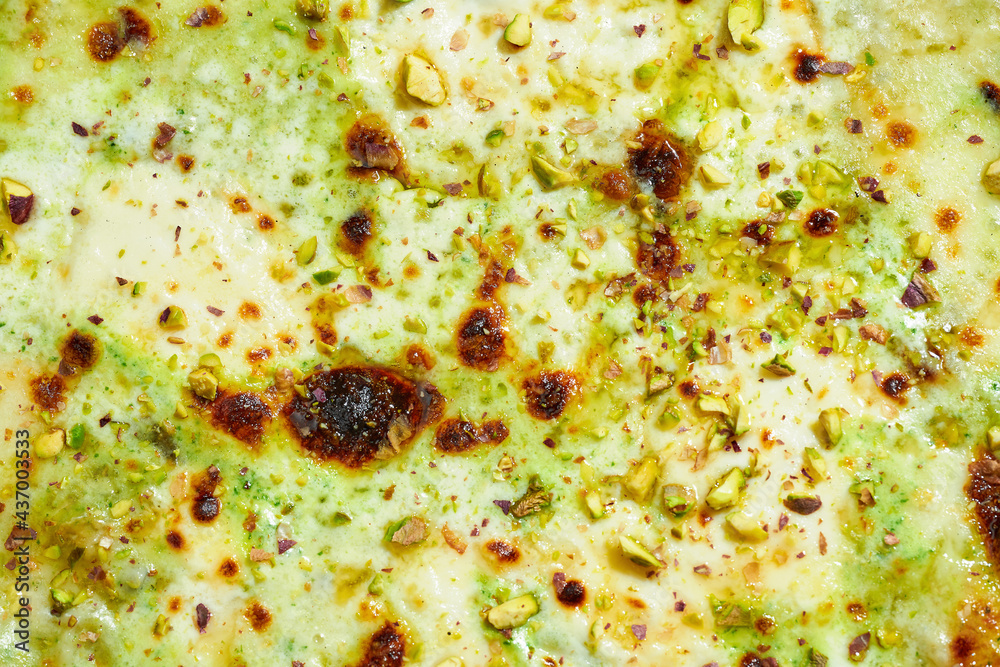 Delicious Italian wood-fired pizza with mozzarella, ricotta, parmesan and pistachios on a gray background. Hard light.