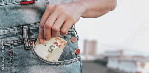 WEB banner format. A womans hand takes out euro from her jeans pocket. The concept of finance, savings, financial expenses. Close-up. Copy space