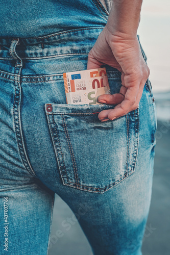 A woman's hand takes out euro bills from the back pocket of her jeans. The concept of finance, savings, financial expenses. Close-up