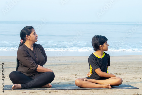 Mother and son practicing yoga at beach