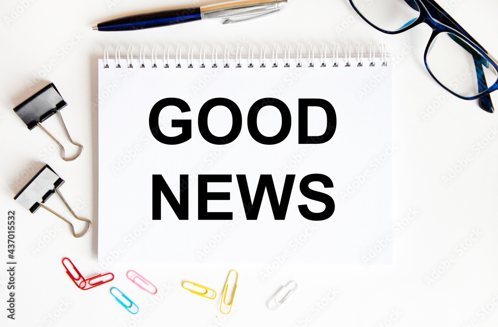 In the notebook text Good News, next to paper clips, scrapeys, glasses, pen, reports. In the notebook text Good News, next to paper clips, scrapeys, glasses, pen, reports.