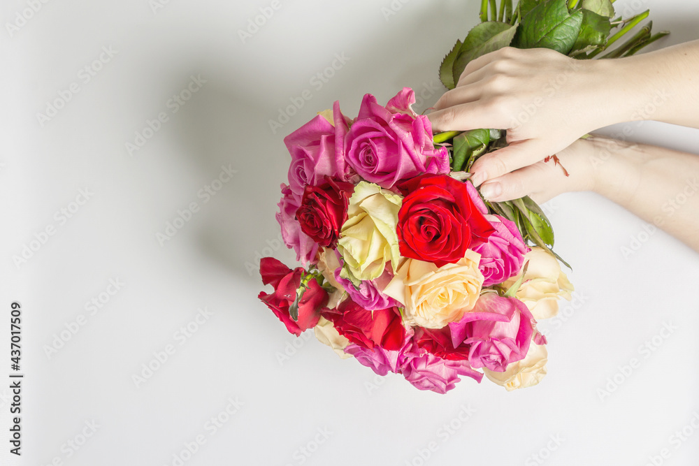 The woman's hands are holding a beautiful bouquet of fresh multicolored roses The woman's hands are holding a beautiful bouquet of fresh multicolored roses