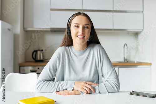 Video chat with friendly young woman wearing headset, webcam view of cheerful female freelancer in headphone talking online, participating in video conference, virtual meeting