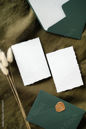 Fotografija Elegant wedding invitation cards and envelopes on green fabric with dried flowers