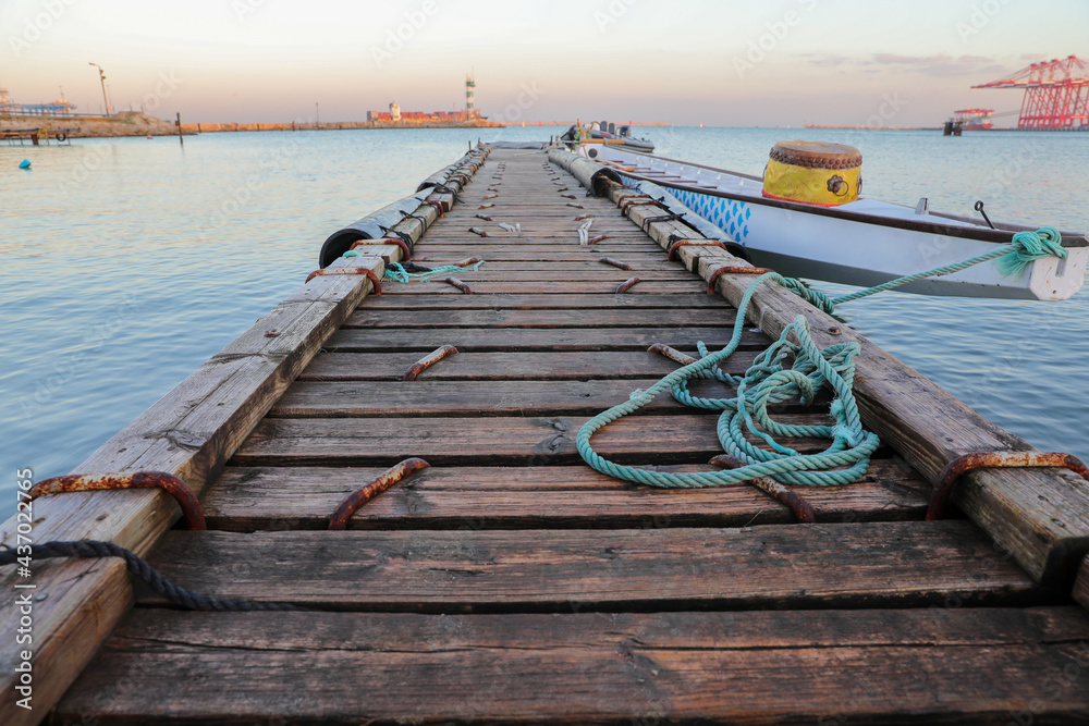 Fototapeta premium Wooden pier with blue sea. Wood floor or terrace beside the blue crystal clear sea, boat and a rope.