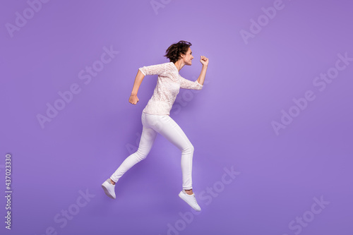Full length photo of charming purposeful young lady dressed white shirt jumping running isolated purple color background