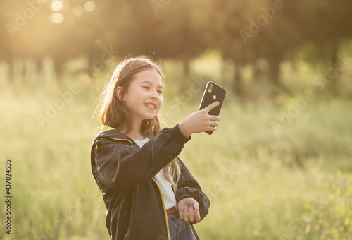 a girl blogger stands with a phone in nature. She broadcasts or takes selfie
