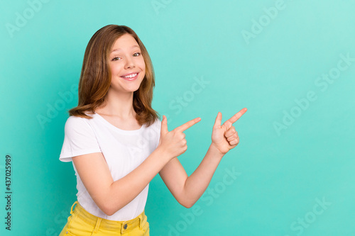 Photo portrait girl smiling pointing finger showing copyspace isolated vivid teal color background