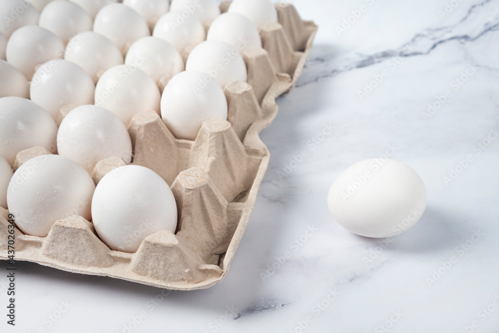 Tray of white fresh eggs on marble table. Raw chicken eggs in egg box. Agricultural industry concept