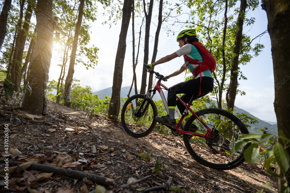 Woman cyclist cycling on mountain top forest trail