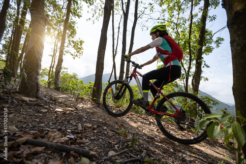 Woman cyclist cycling on mountain top forest trail