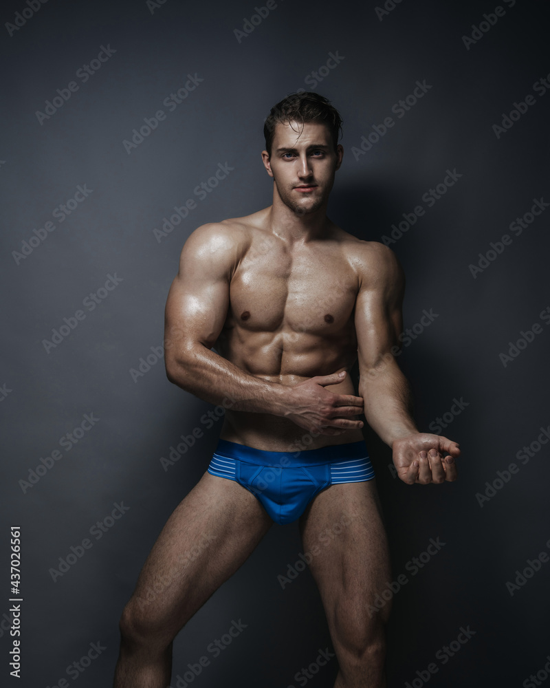 Fototapeta premium Shirtless man in blue underwear at grey background in studio