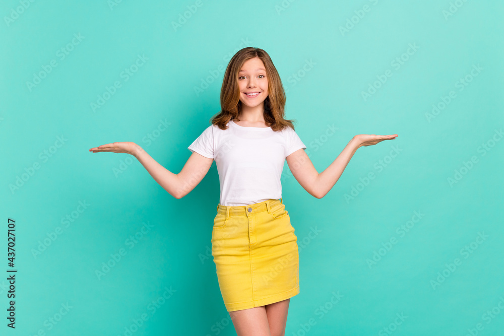 Photo portrait girl comparing copyspaces on hands isolated vibrant teal color background Photo portrait girl comparing copyspaces on hands isolated vibrant teal color background