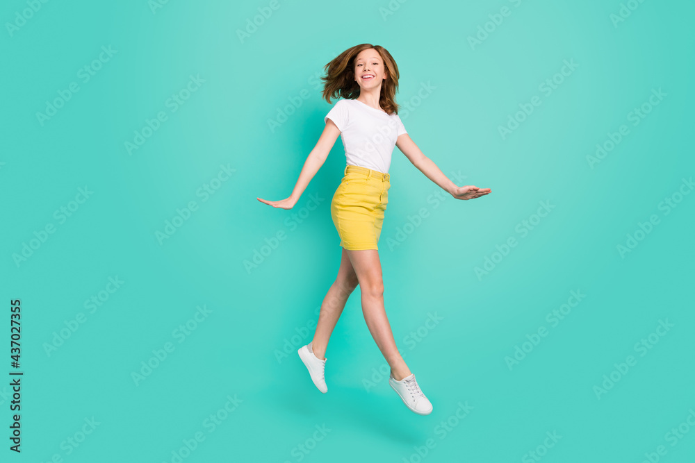 Full length body size photo smiling schoolgirl jumping up careless isolated vivid teal color background Full length body size photo smiling schoolgirl jumping up careless isolated vivid teal color background