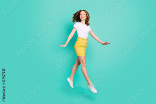 Full length body size photo smiling schoolgirl jumping up careless isolated vivid teal color background