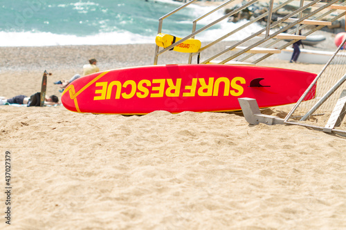 Obraz na plátně Orange surf lifesaving surfboard on the sand at the foot of the lifeguard stand, selective focus