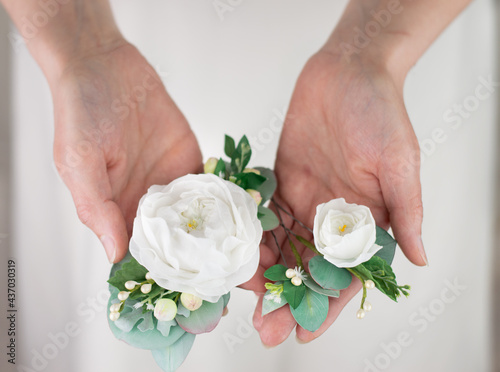 Blurred image of a flower hair ornament in the hands of the bride.