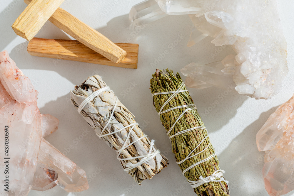 White sage, cedar, crystals, and Palo Santo sticks tied by a bundle on a light background. A set of incense for fumigation. Top view. Organic incense from Latin America. Color photo close-up. - obrazy, fototapety, plakaty 