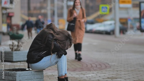 The girl is crying on the street of the city. A sympathetic passer-by calms a lonely girl.
