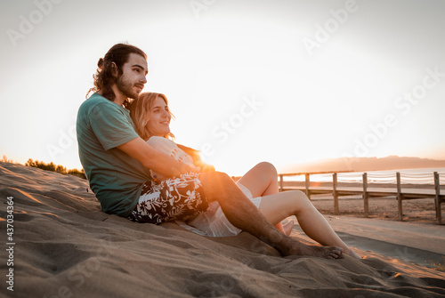 Romantic couple embracing and lying on sandy beach at sunset