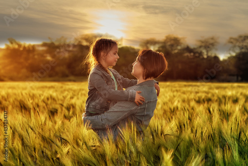 Portrait of happy mom and daughter in the field at sunset