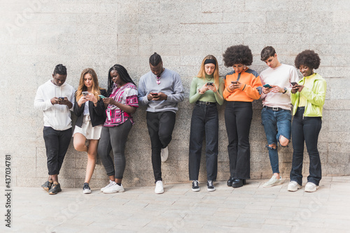 Multiracial friends chatting on smartphones on pavement photo