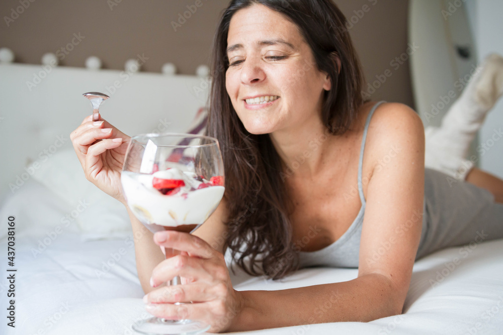 Attractive middle-aged brunette Spanish woman posing with a glass of ice cream with fruits Attractive middle-aged brunette Spanish woman posing with a glass of ice cream with fruits