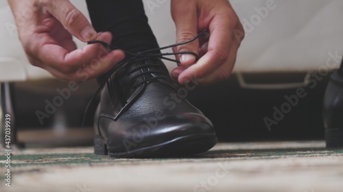 The man is tying the shnzrki on black shoes. Putting on men's shoes in the morning before going to work. Hands close-up © Валерий Зотьев