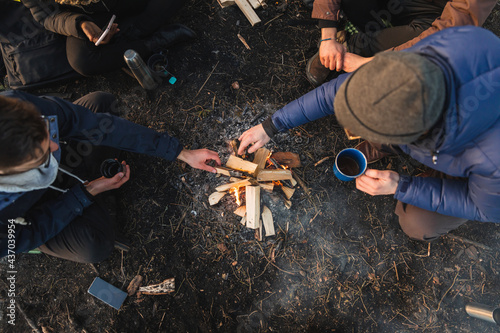 Multiethnic campers lighting fire on lake coast photo